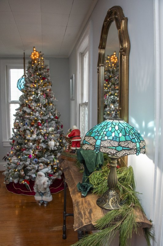 A blue Tiffany lamp sits atop a live edge side table leading to one of the five thematically decorated trees in different rooms of Peggy and Ed Duckworth’s Mulberry Street home.